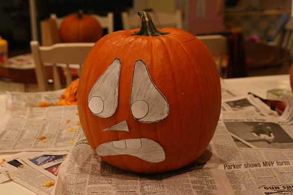 Using a paper cutout to check the face design of the pumpkin
