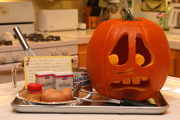 Scared and terrified pumpkin looking at recipe card and ingredients for pumpkin pie